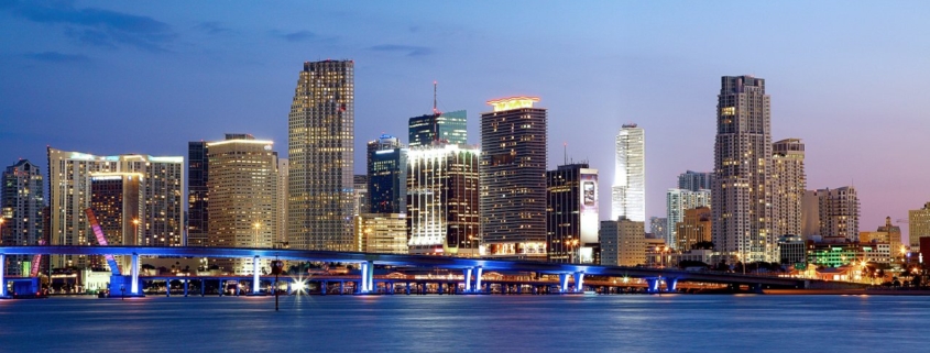City skyline at dusk with illuminated buildings.