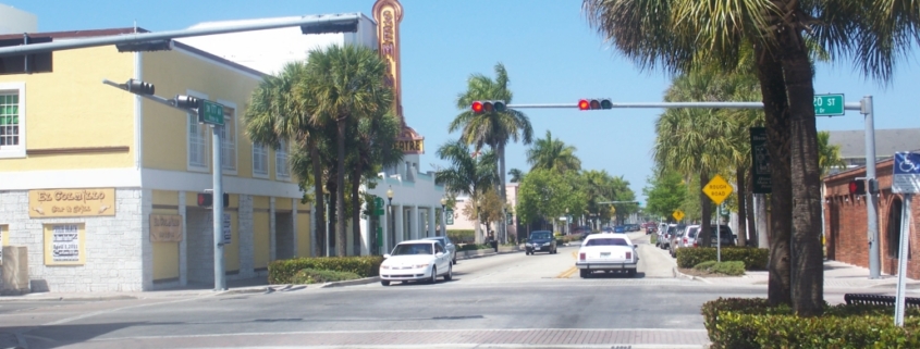 Street intersection with palm trees and buildings.