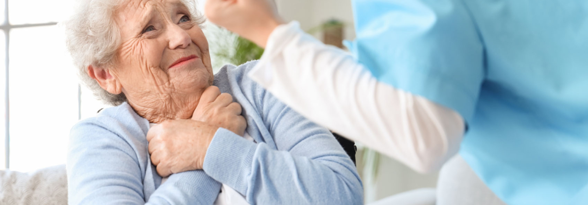 Elderly woman smiling at caregiver indoors.