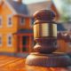 Gavel in front of miniature house model.