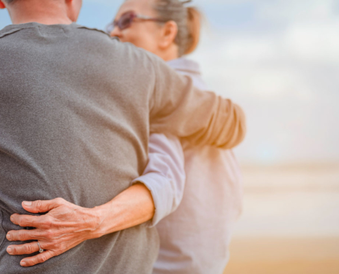 Elderly couple embracing on a beach.